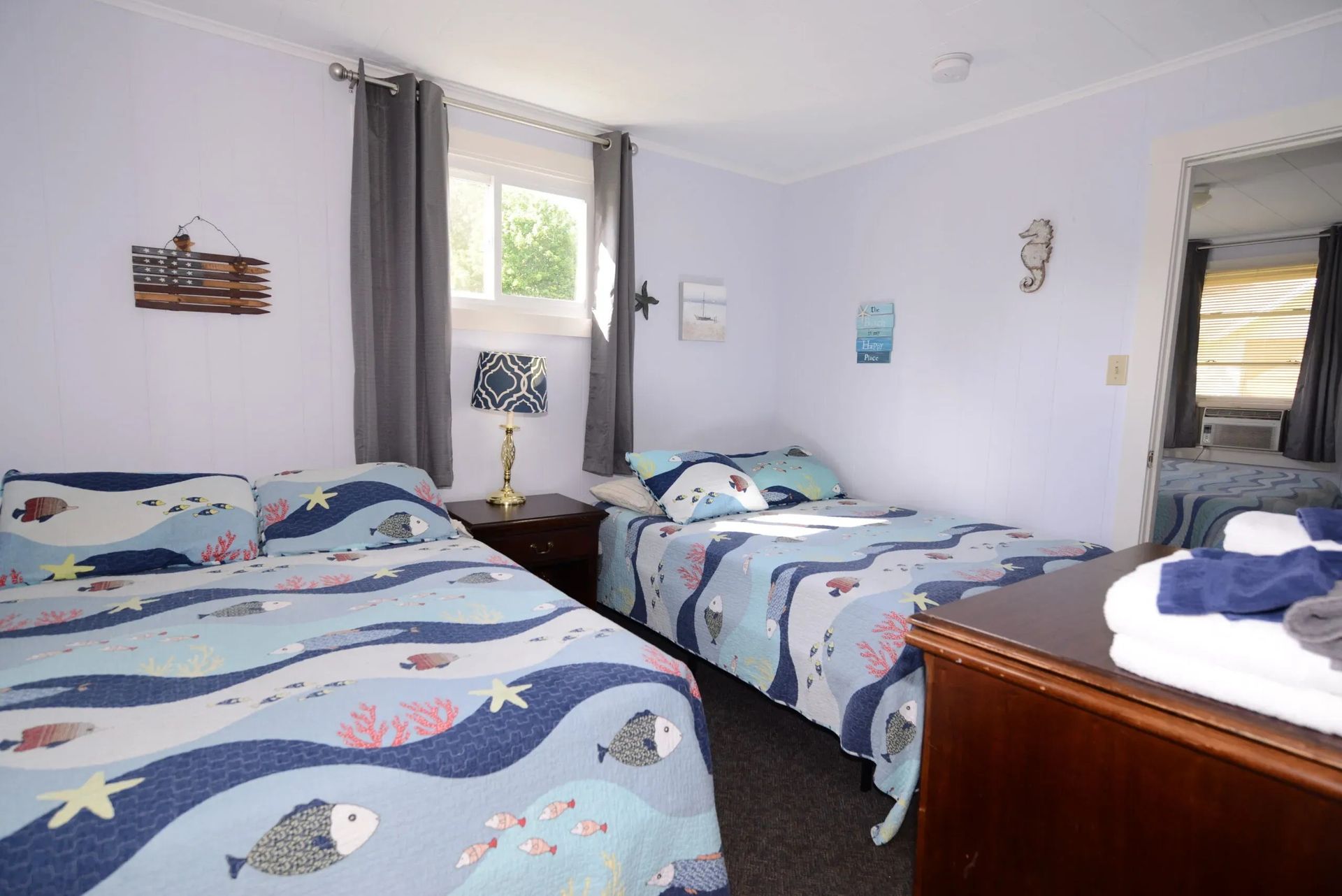 Two twin beds in a room with ocean-themed bedding and decor.