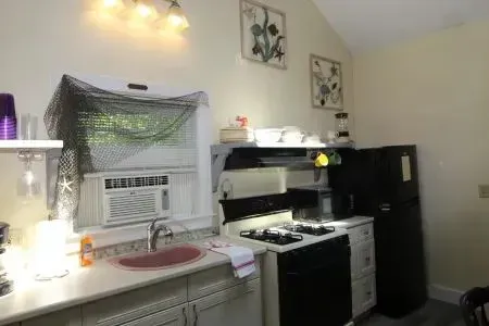 Small kitchen with stove, refrigerator, sink, and decorative items.