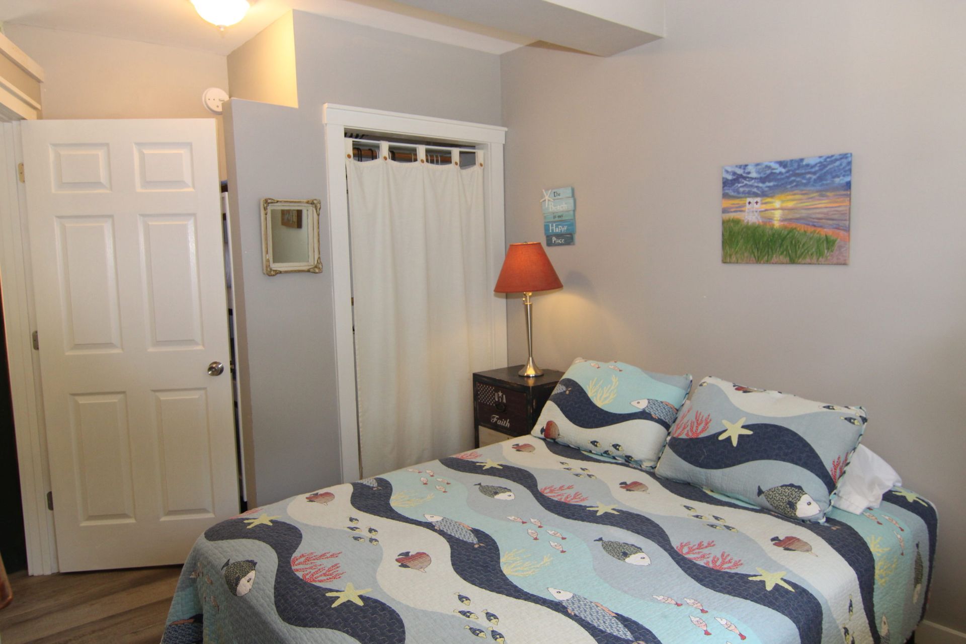 Bedroom with a bed, artwork, lamp, and closet. 