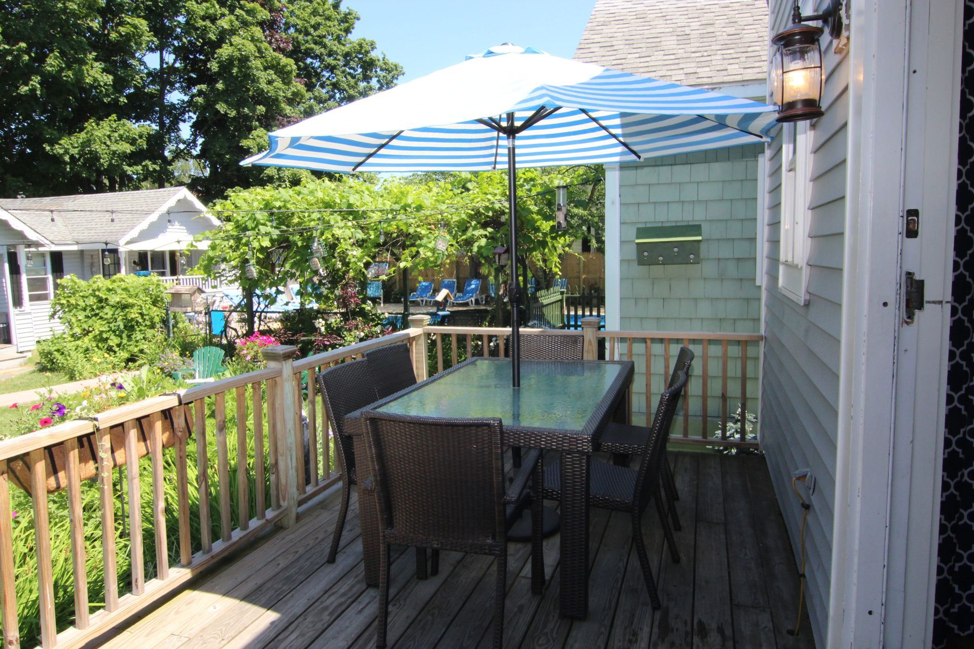 Patio with table and chairs under a blue and white striped umbrella.