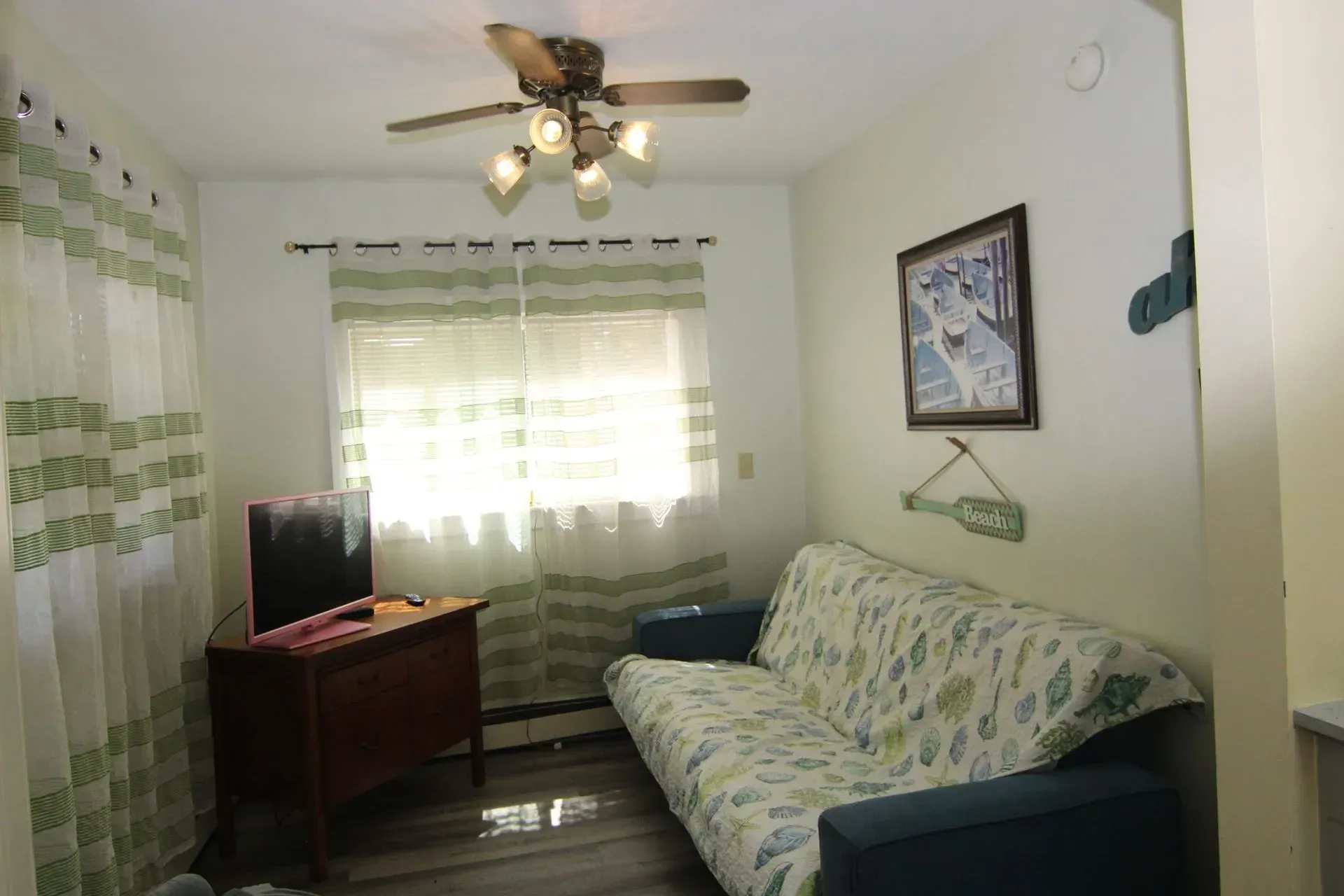 Small room with a futon, TV, and window. 