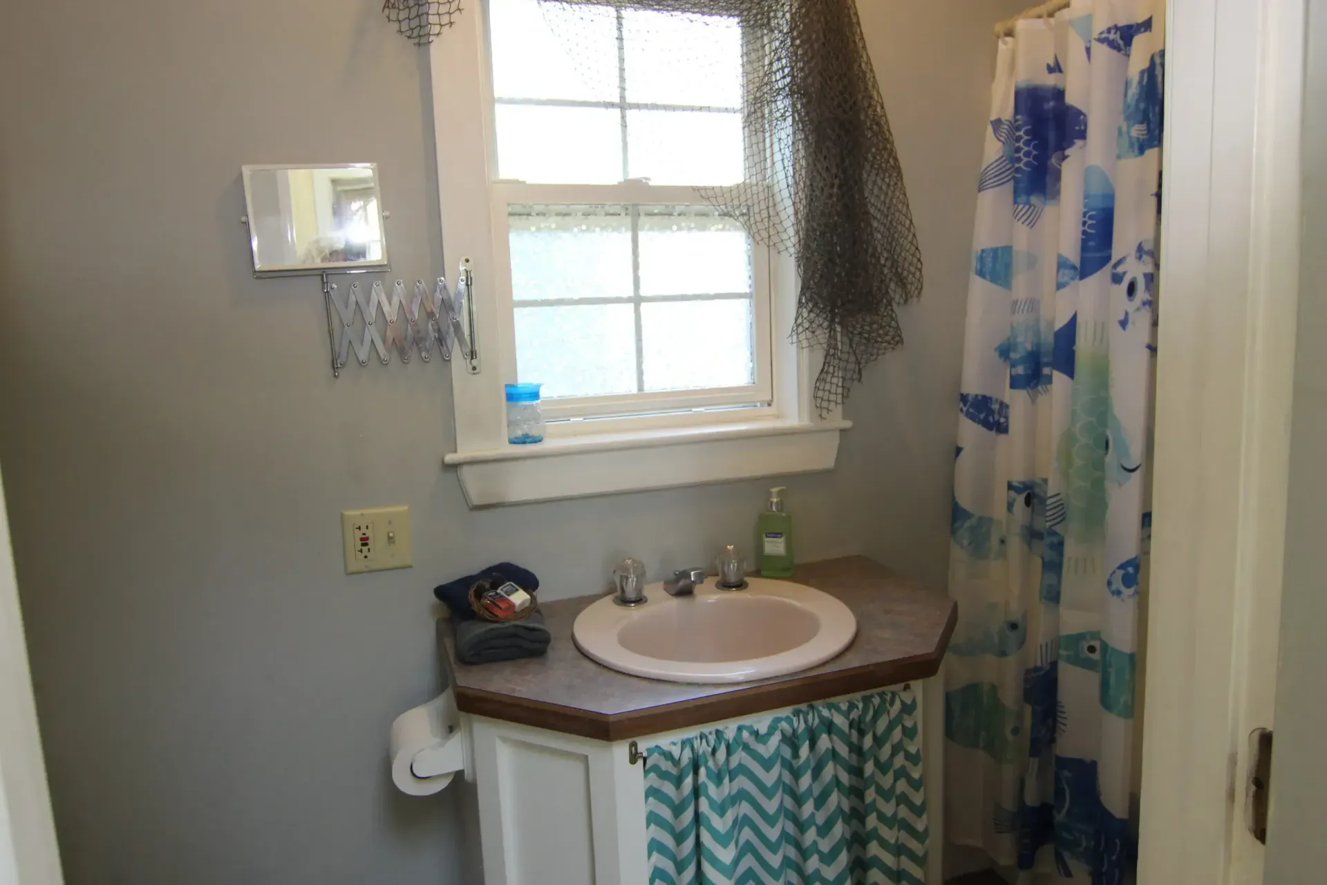 Bathroom with a sink, window, shower curtain, and a wall-mounted mirror.