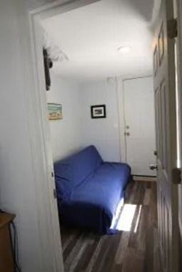 A narrow room with a blue futon, white door, and framed art. 