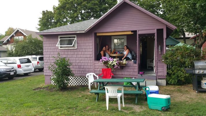 Purple cottage with people sitting in the porch. 