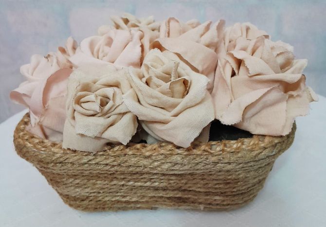 Rosas de tela en una cesta tejida. Las flores son de color melocotón y la cesta es de color canela.
