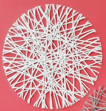 Diseño de hilo blanco sobre fondo rojo. El hilo está tejido en un patrón circular que recuerda a un copo de nieve.