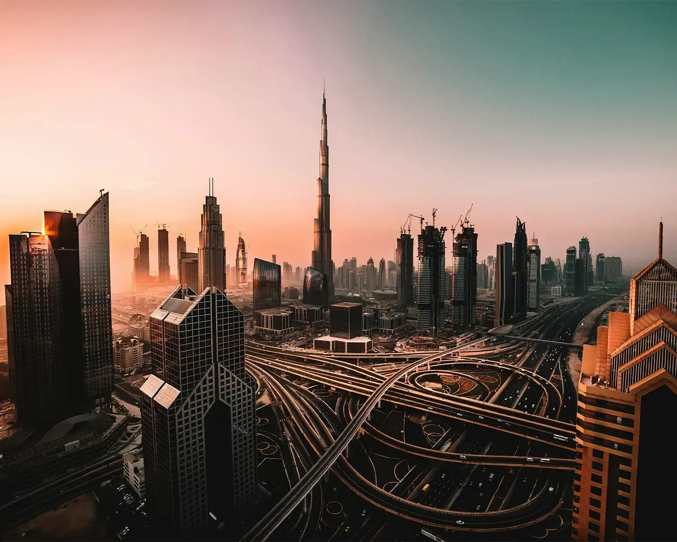 Aerial view of Dubai at sunset, showcasing the Burj Khalifa surrounded by modern skyscrapers and int