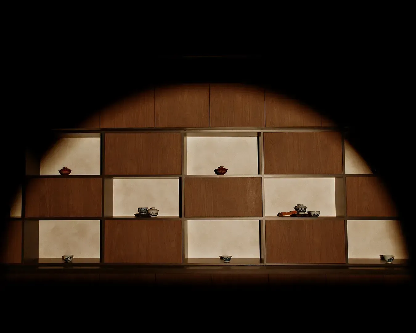 A beautifully arranged shelf displaying delicate Chinese teacups and teapots, carefully organised 