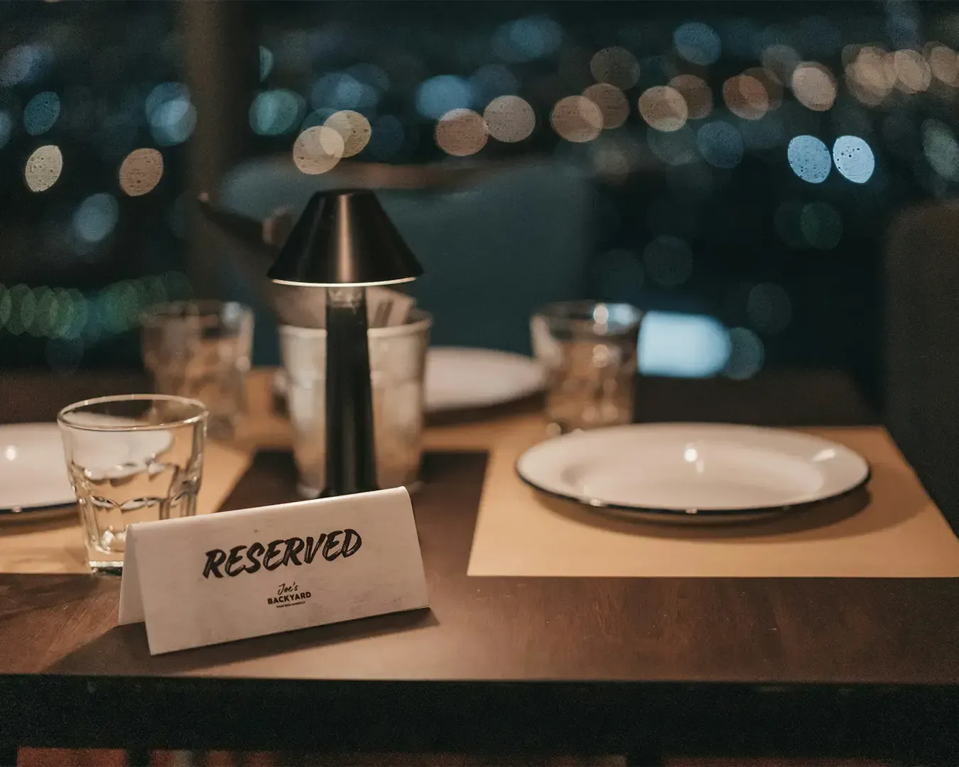 A neatly placed “Reserved” sign sits on a well-set restaurant table, indicating the table is booked 