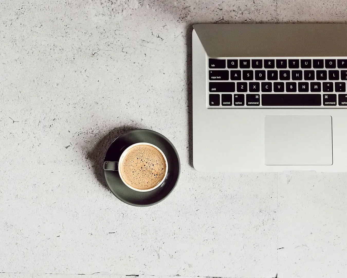 A laptop placed on a clean table beside a cup of coffee, creating a calm and focused workspace. 