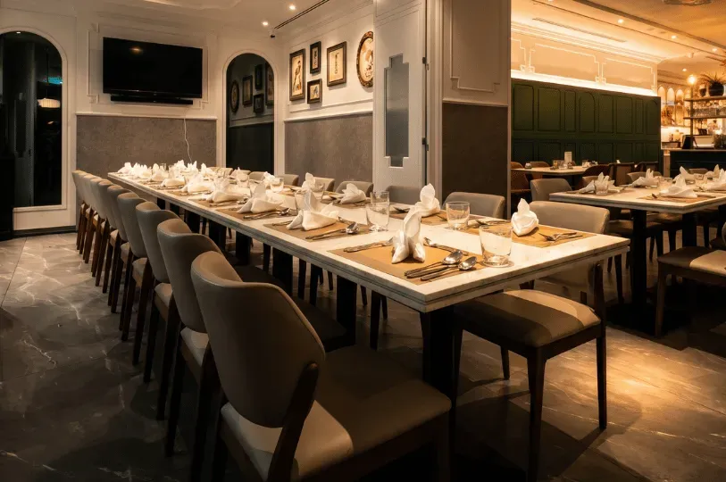 A long, elegant marble dining table meticulously set for a large group in a sophisticated restaurant