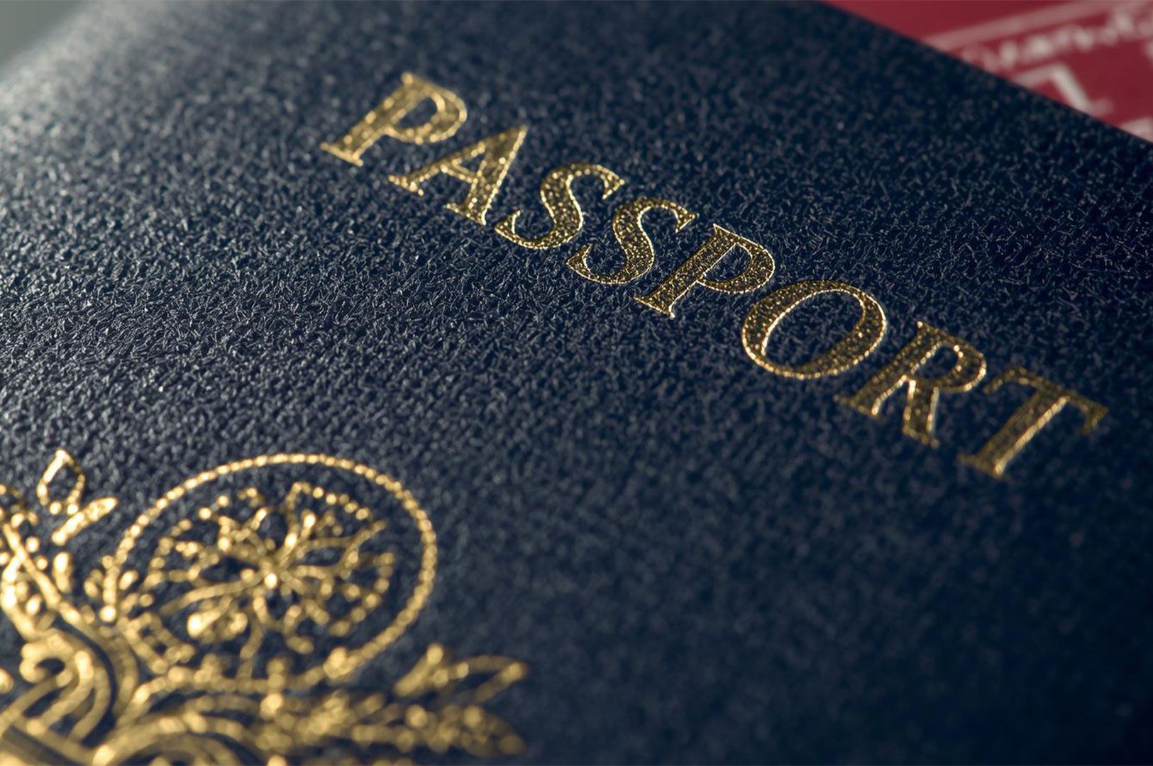 Extreme close-up of the textured cover of a dark blue passport, featuring the word 