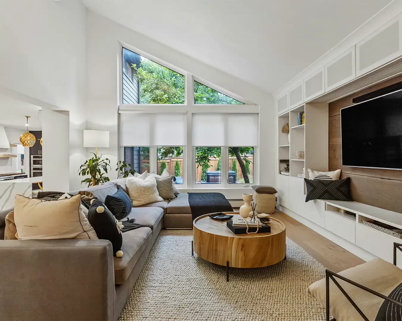 A spacious modern living room filled with natural light streaming through large windows. Minimalist furniture and neutral tones create a bright, airy, and comfortable environment.