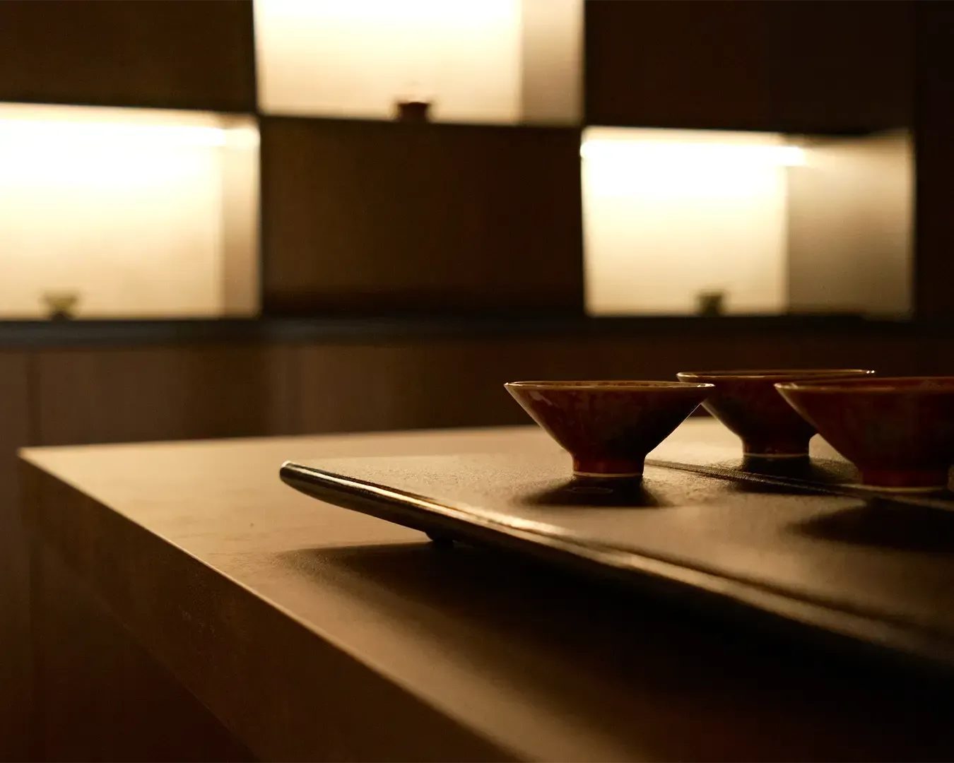 Three traditional Chinese teacups placed neatly on a wooden tea table, highlighting minimalist tea culture and the quiet elegance of a traditional tea-serving setup.