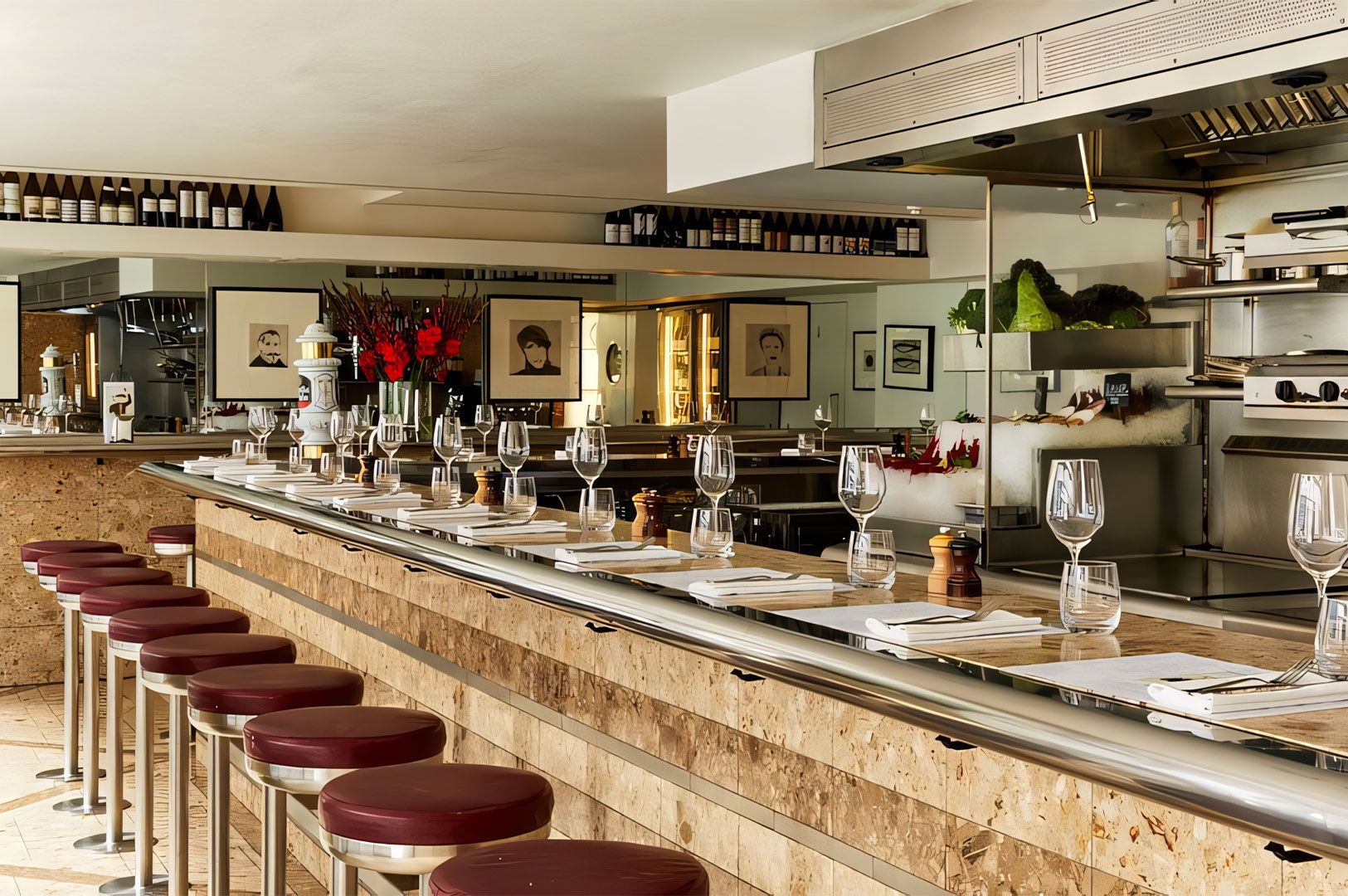 The sleek, modern interior of a Spanish tapas bar (like Barrafina), featuring a long, light-colored stone counter with rows of red leather bar stools and place settings.