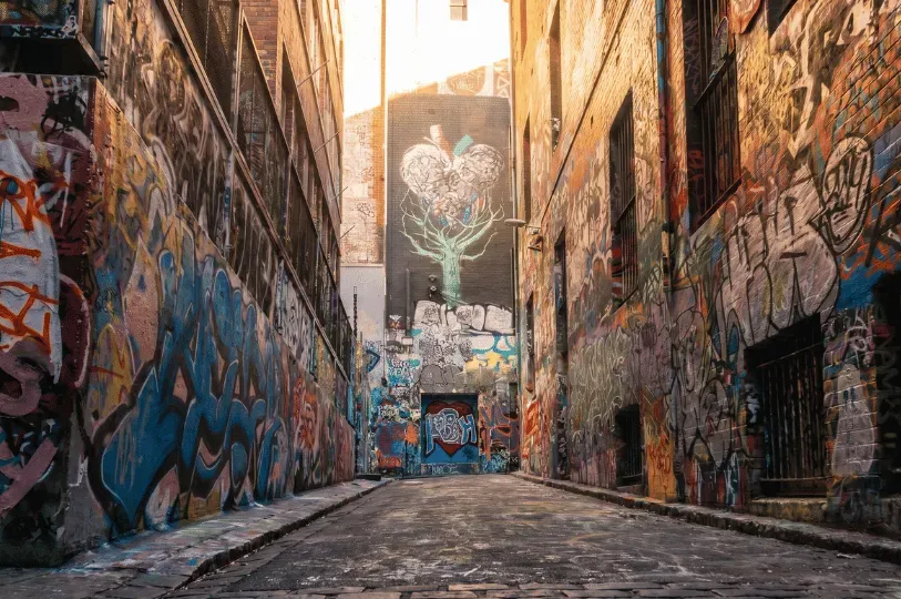 A cobblestone Melbourne laneway heavily decorated with vibrant street art and graffiti, a classic backdrop for the city's hidden venues.