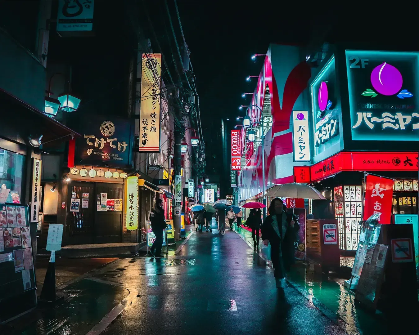 A bustling Tokyo street glowing with neon signs and illuminated billboards, with pedestrians walking along the pavement. The scene feels dynamic and modern, showcasing the city’s iconic nightlife and urban charm.