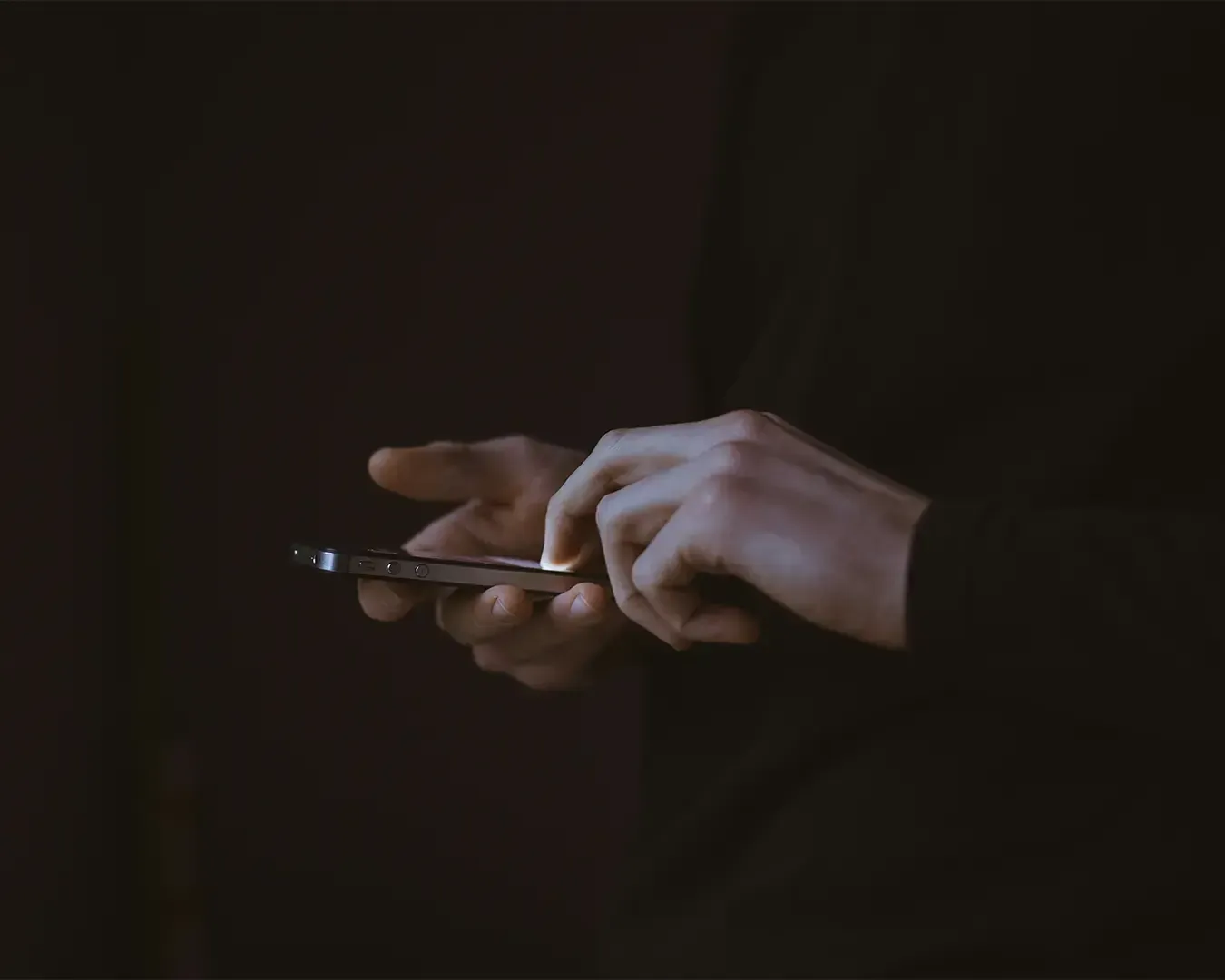 A hand holding a smartphone while looking at the screen, suggesting someone checking messages, browsing, or managing tasks on their device. The close-up view highlights everyday digital interaction.