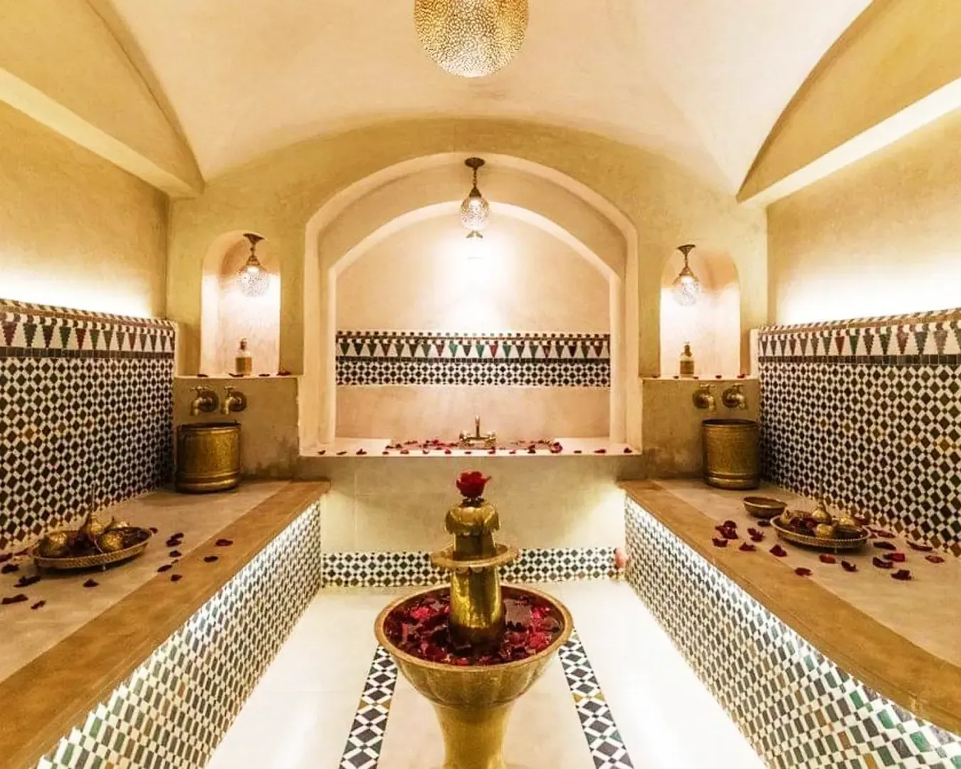 Luxurious hammam with ornate tiles, dim lighting, rose petals, and a central fountain, creating a serene and opulent ambiance.