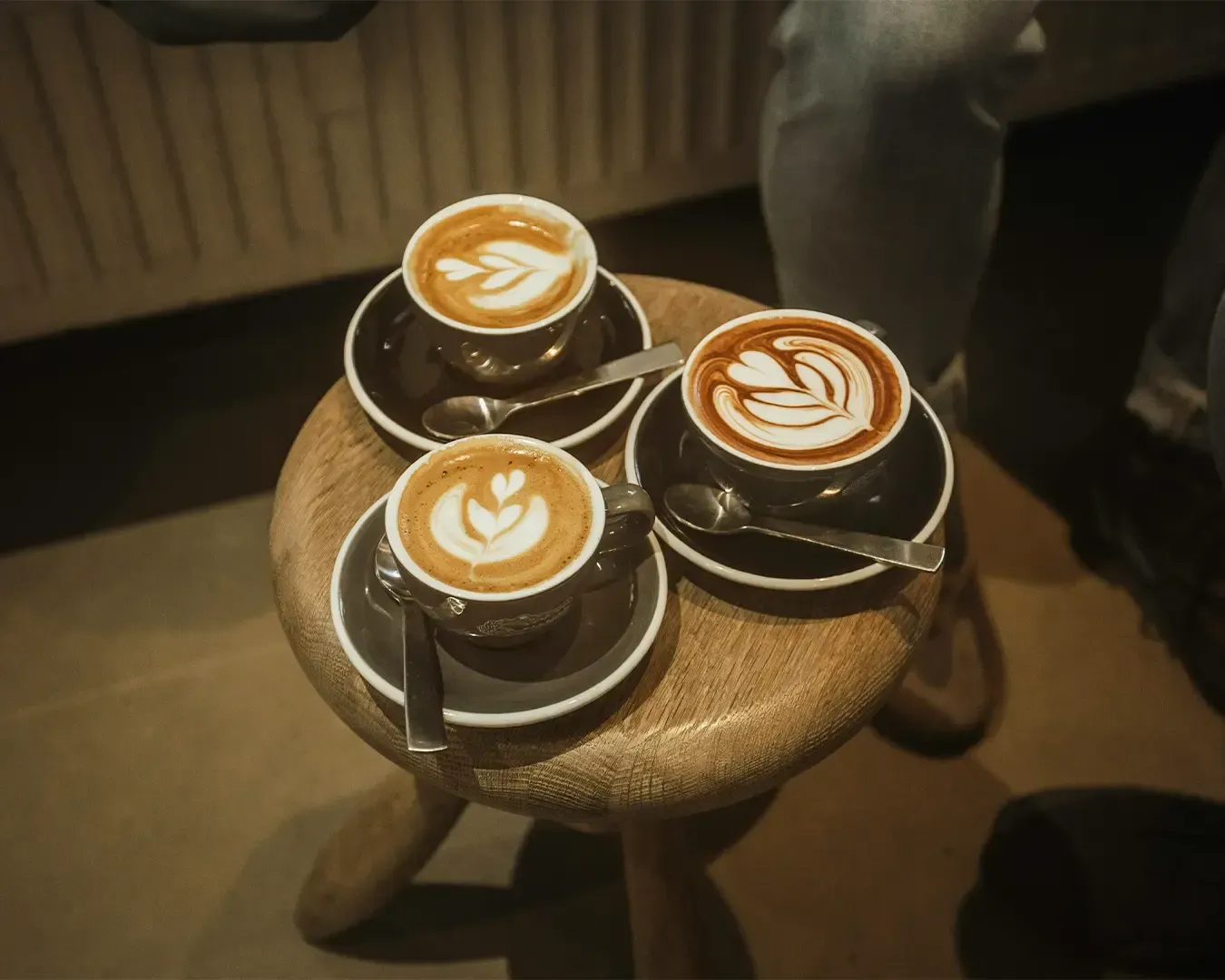 Three cups of freshly brewed coffee arranged together, each topped with detailed latte art patterns, creating a visually appealing café presentation.