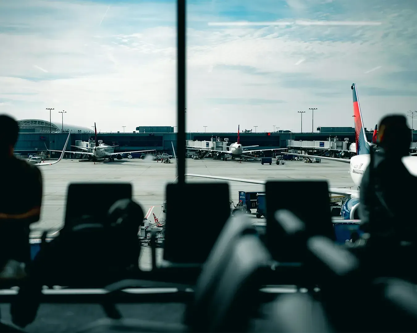 A view from inside an airport terminal looking through large glass windows at an airplane parked on the runway. The scene captures the anticipation and movement of air travel.