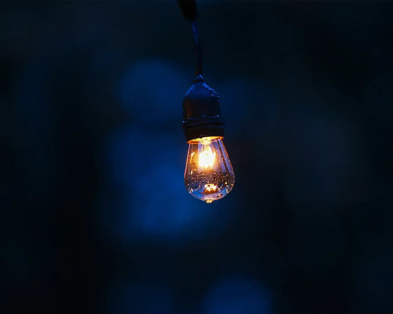A glowing light bulb hanging from the ceiling, casting a warm soft light. The simple design highlights the bulb as a symbol of creativity, ideas, or illumination.