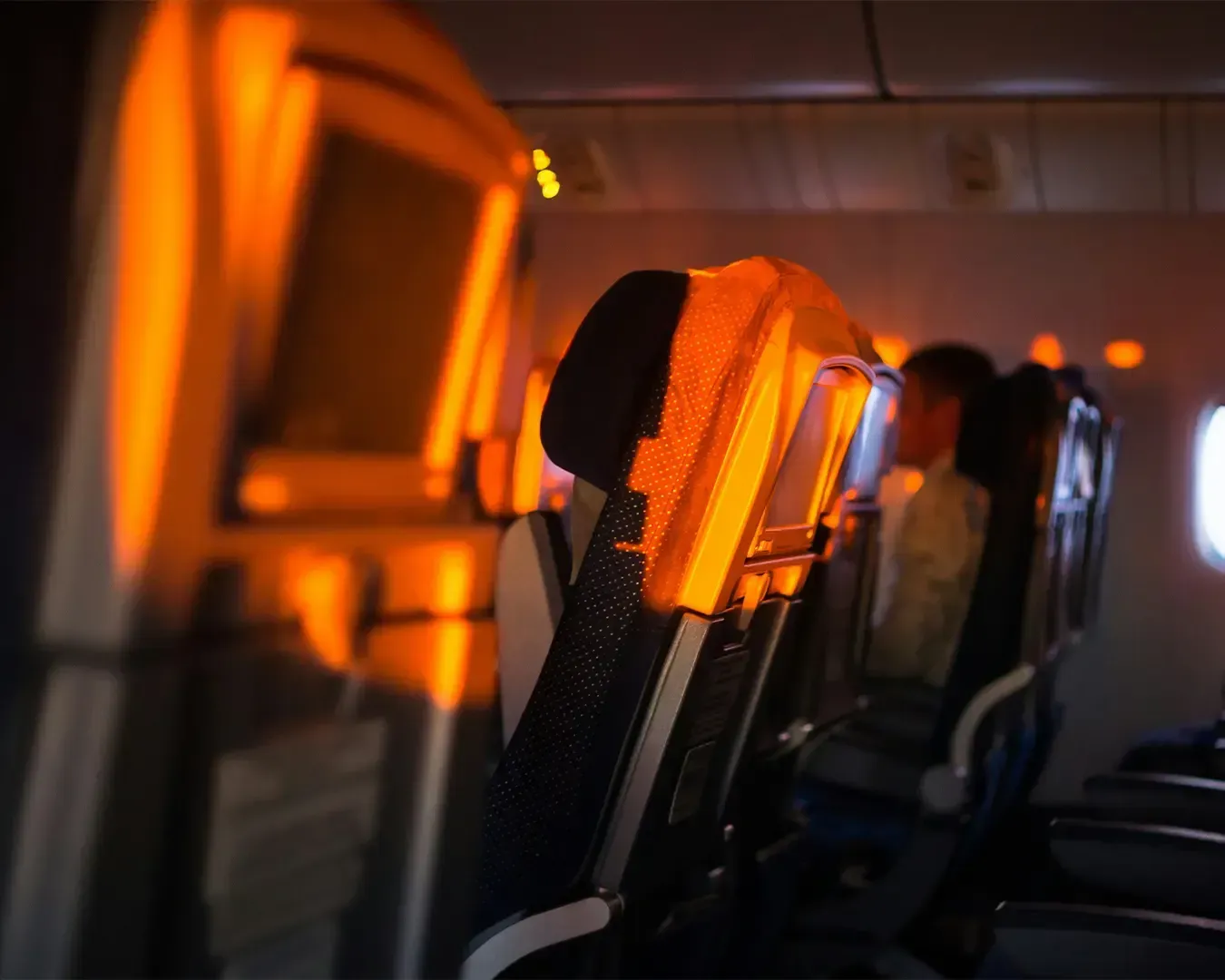 A peaceful view from an airplane seat where warm sunlight streams through the window, illuminating the cabin and creating a quiet moment during flight.