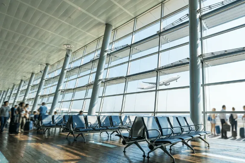 A bright, expansive modern airport terminal featuring large slanted architectural pillars and floor-
