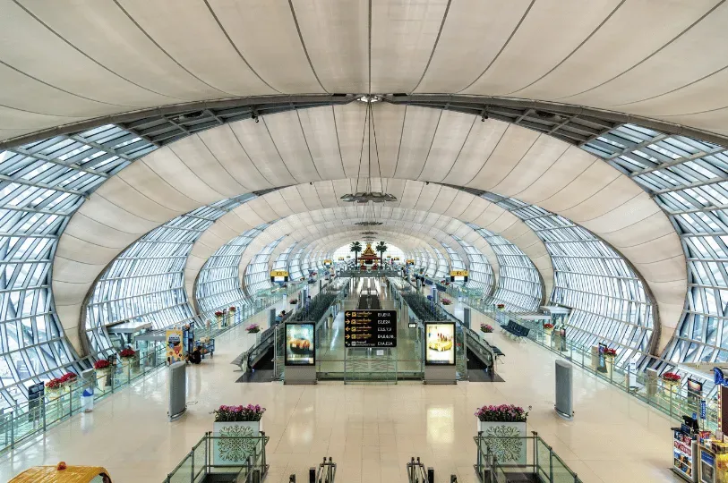 Wide interior view of Bangkok's Suvarnabhumi Airport, highlighting its highly modern, vaulted steel-