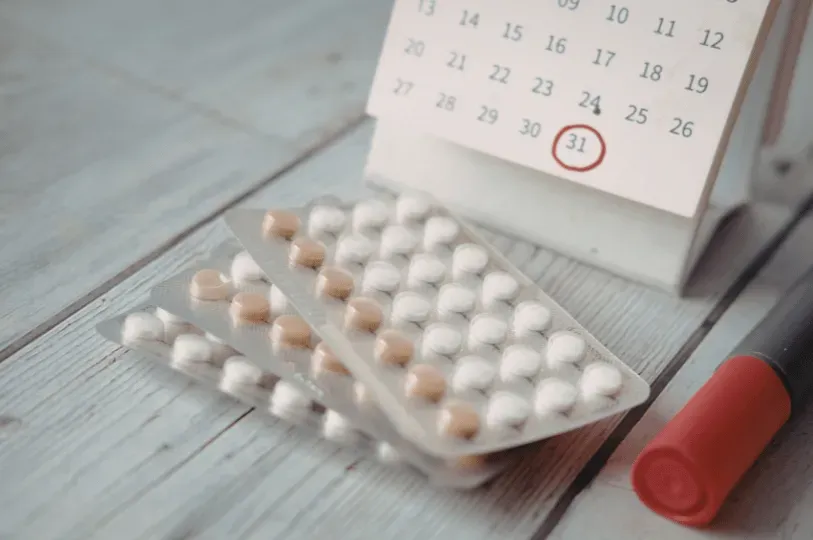  A close-up of two blister packs of white and tan pills resting on a wooden surface. This suggests the scheduled use of supplements or medication for managing sleep cycles.