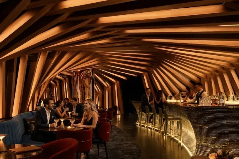 Patrons enjoy drinks inside a sophisticated Melbourne hidden bar featuring a striking, undulating wo