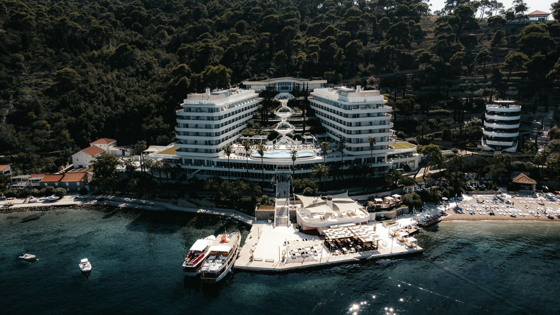 5 Ultra-Luxury Hotels: Panoramic drone shot of a high-end island resort blending seamlessly with nat