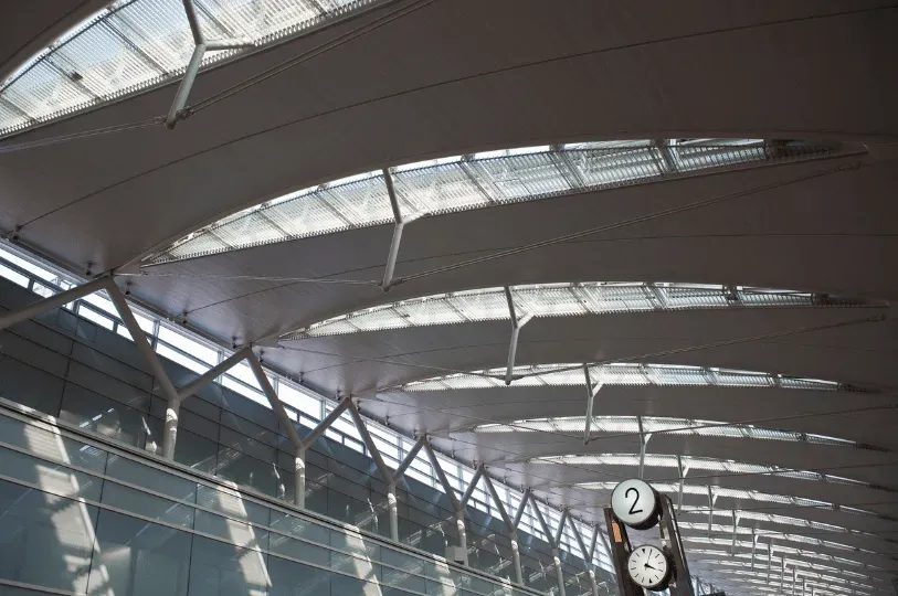 Looking up at the modern, curved architectural ceiling and skylights of a spacious Tokyo transit hub