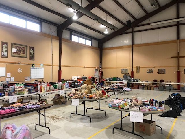A large, well-lit hall with several tables covered in various items, suggesting a community rummage sale or donation event.