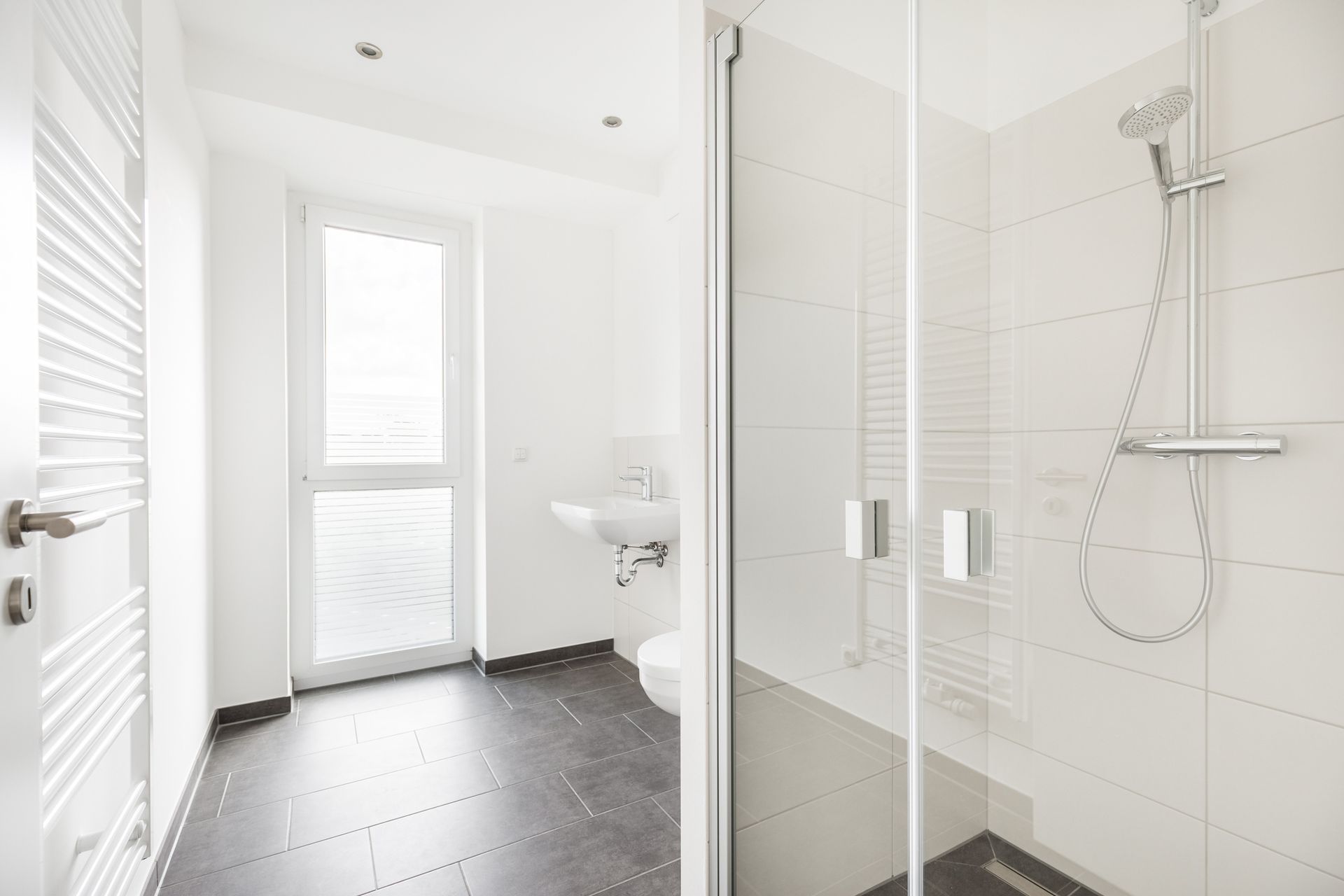A bathroom with a shower , sink , toilet and window.