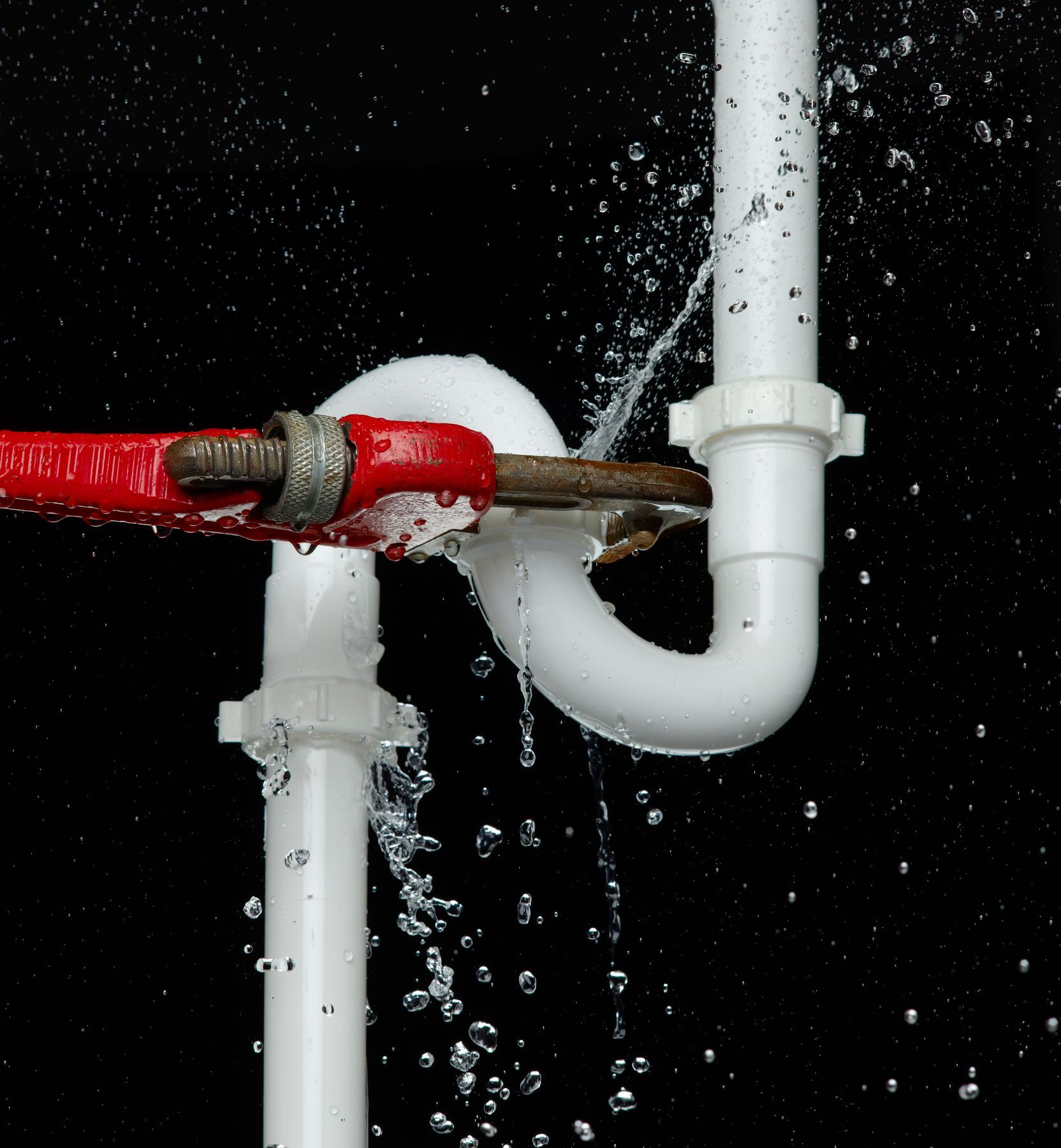 Wrench on leaking pipe over black background, representing emergency residential plumber services. Wrench on leaking pipe over black background, representing emergency residential plumber services.