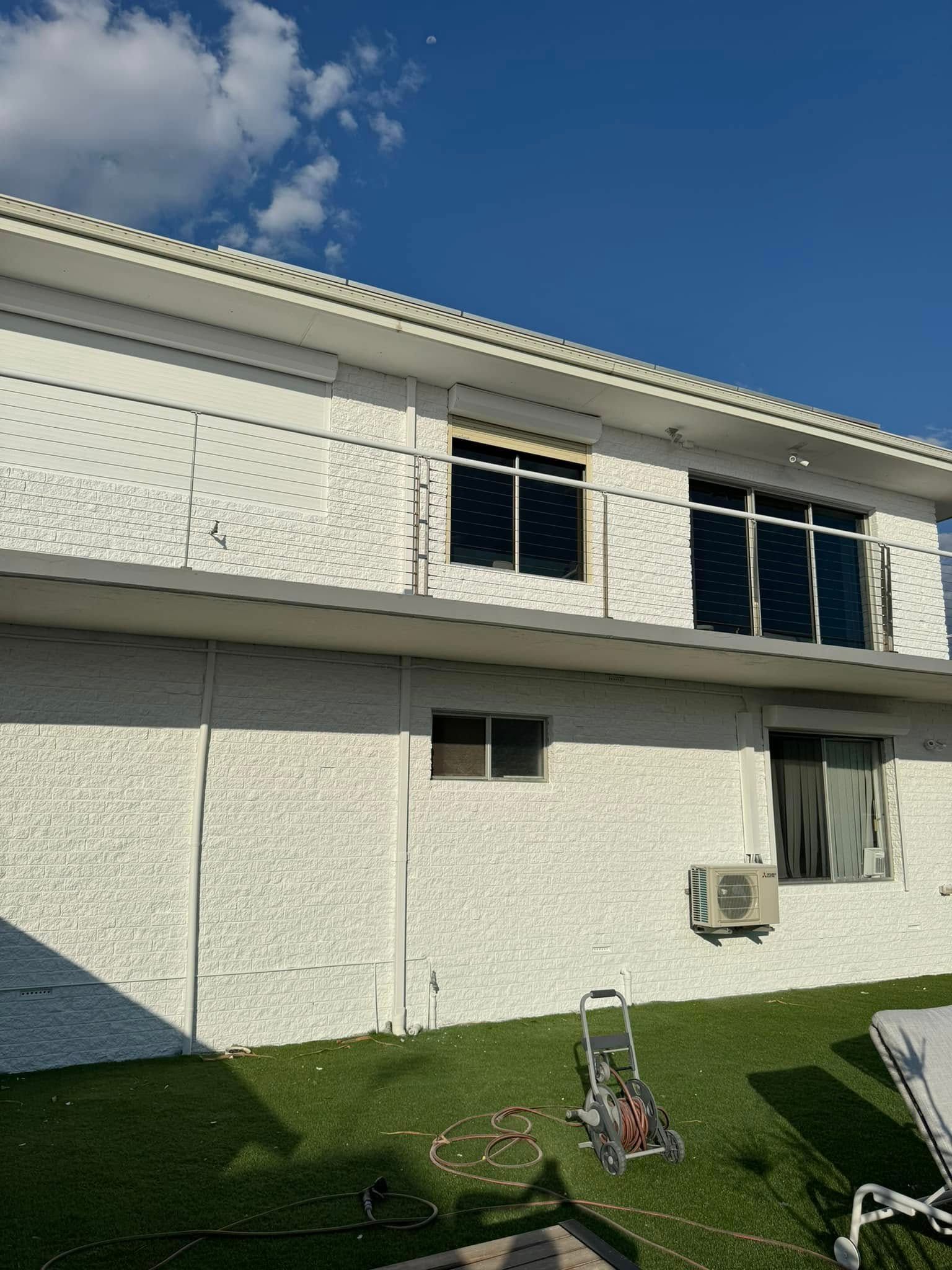 White stucco building with black-framed windows, a small lawn, and blue sky.