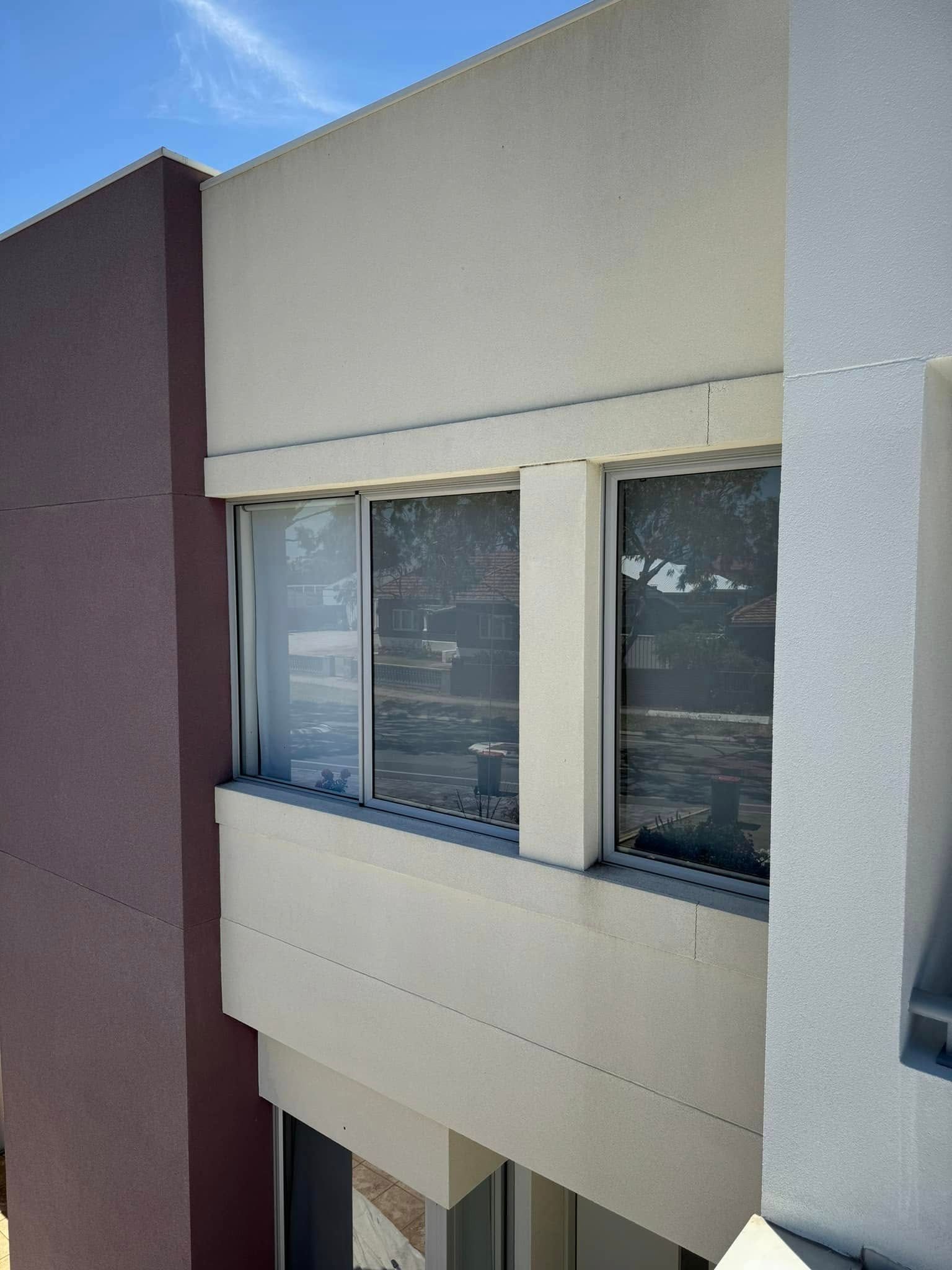 Exterior view of a building with two windows, painted in shades of brown and white against a blue sky.