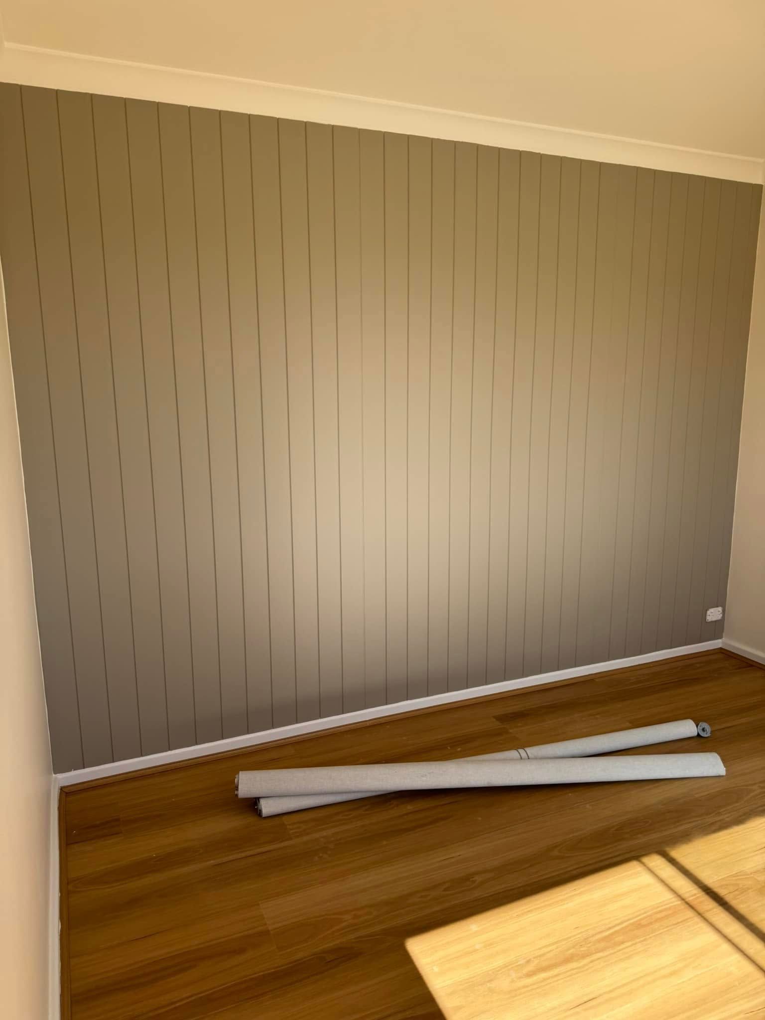 Gray textured accent wall with vertical lines in a room with hardwood flooring.