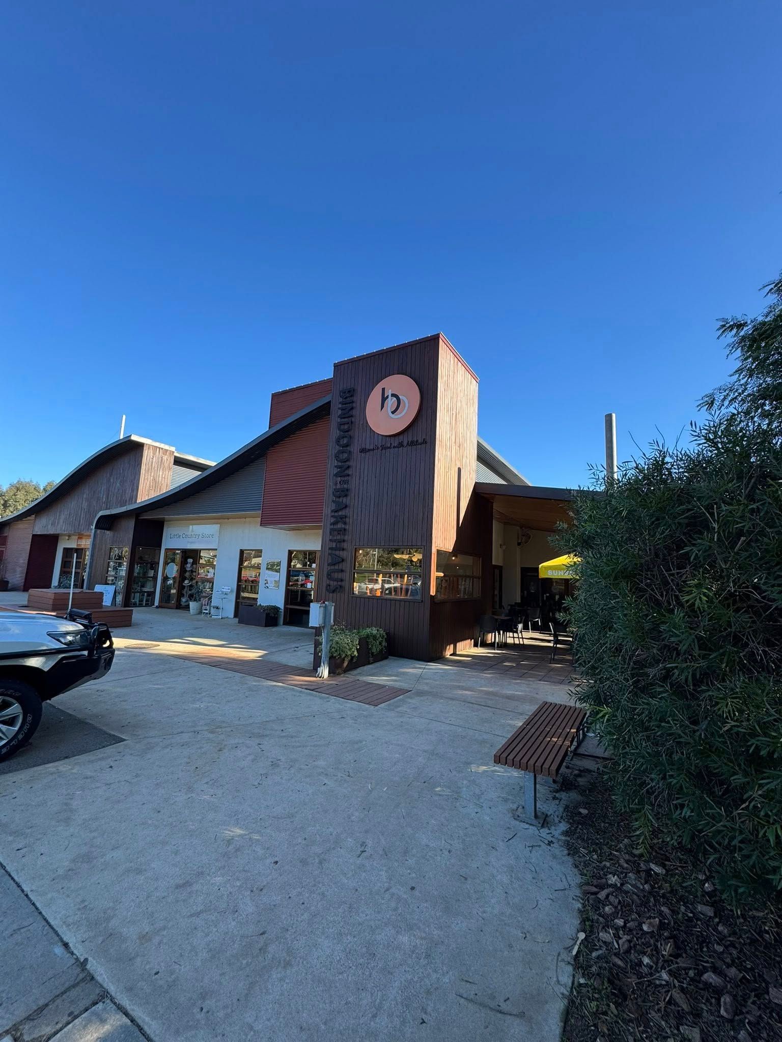 Building with orange accents, sign, and outdoor seating area on a sunny day.