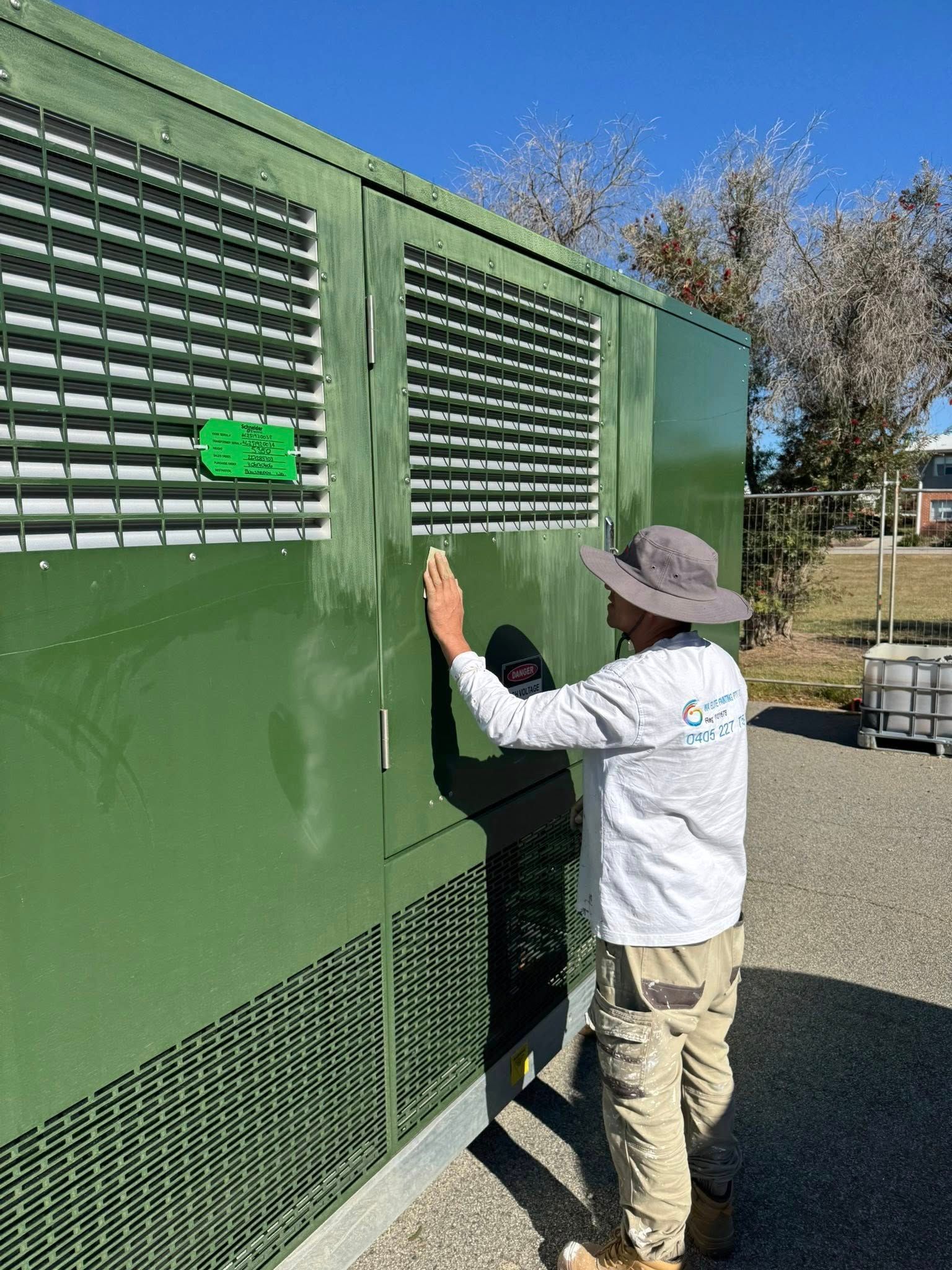 Person painting a white wall with a paint roller outdoors, casting a shadow.