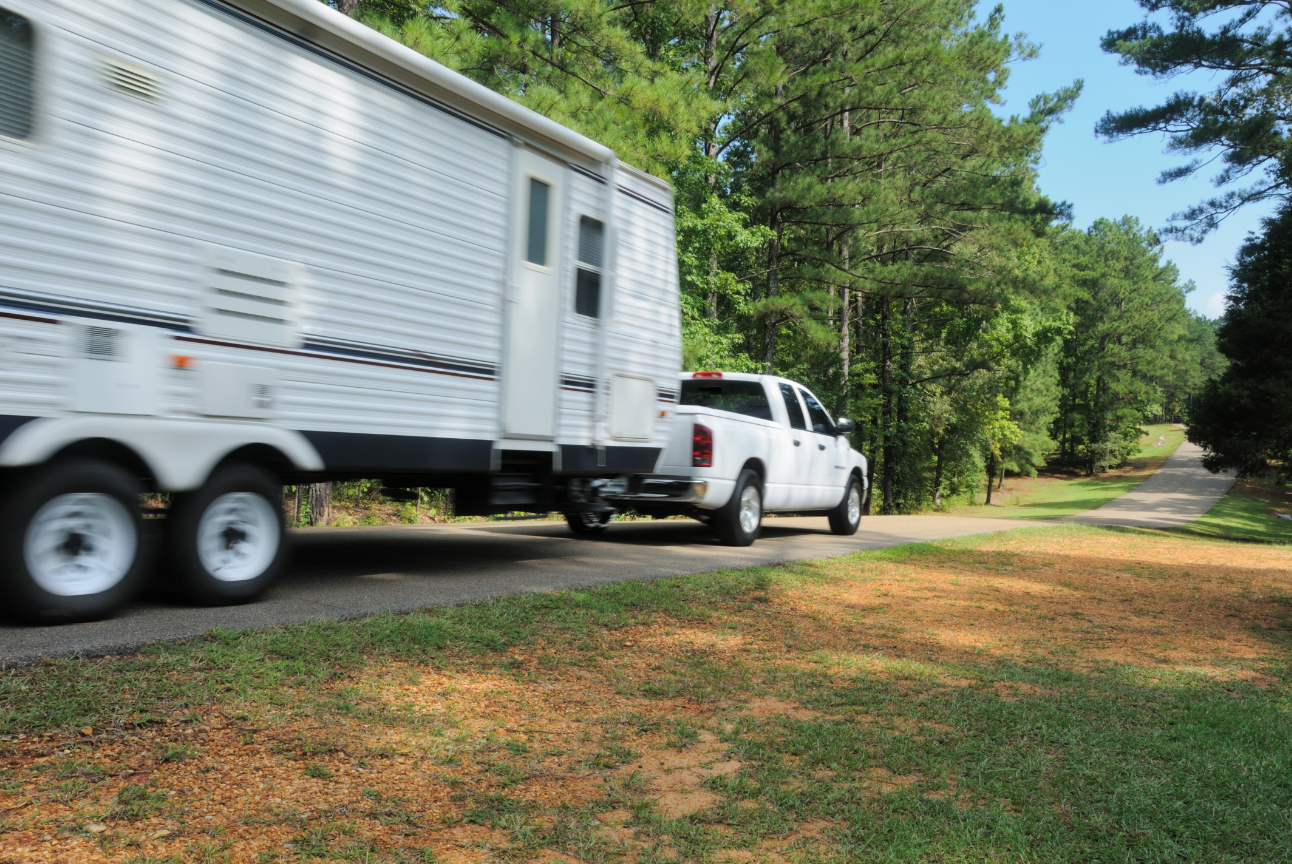 A truck is towing a trailer down a road.