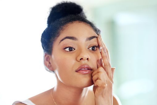 Woman looking at her reflection, touching her face with one finger.