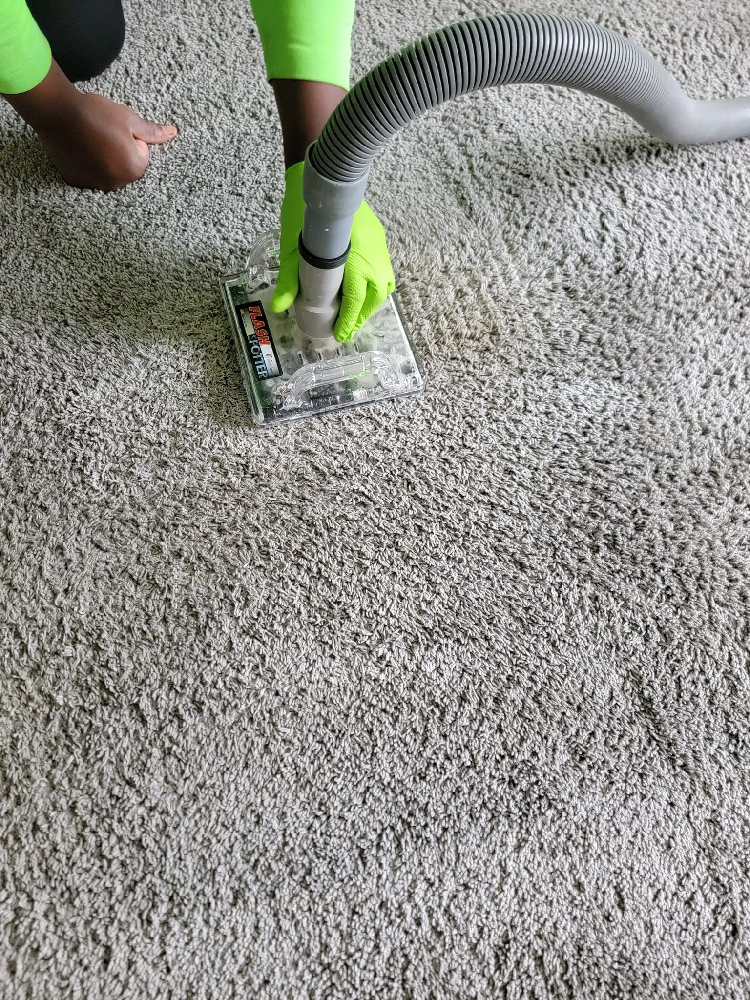 A person is using a vacuum cleaner to clean a carpet.