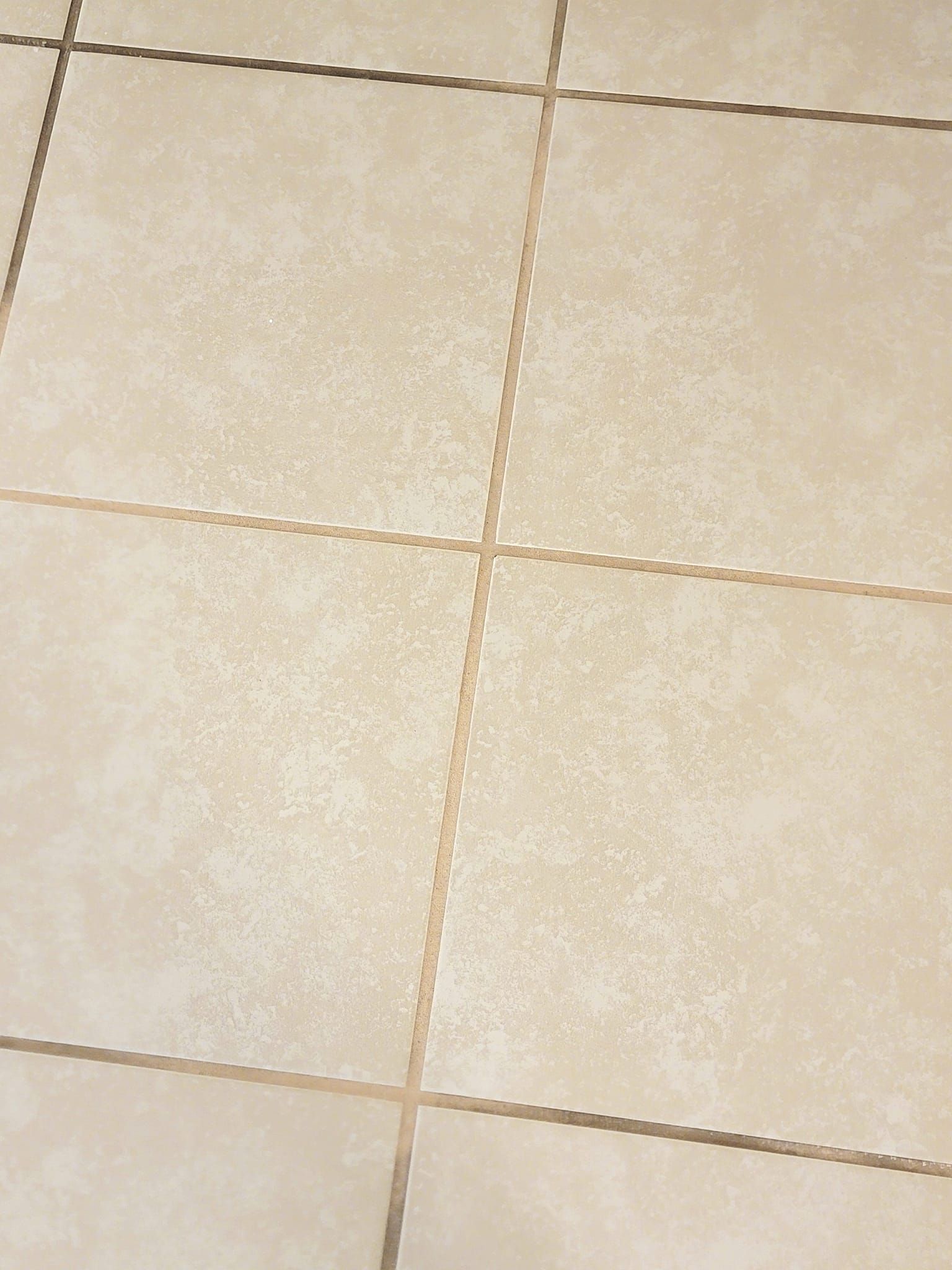A close up of a tiled floor with a few cracks in it.