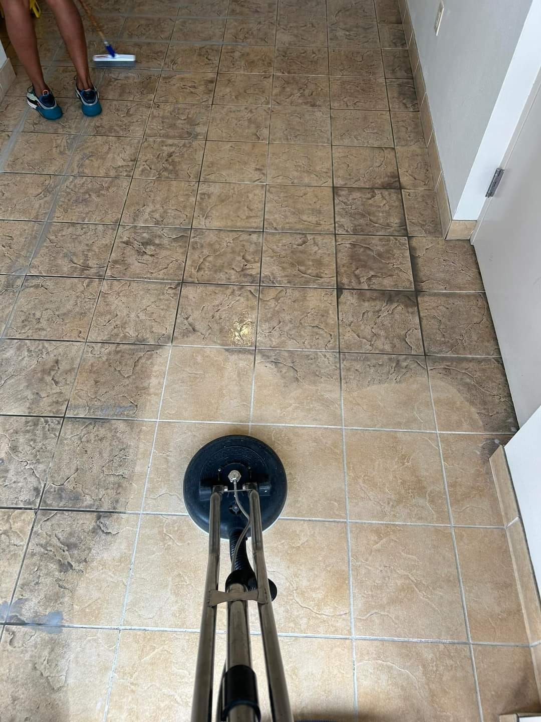 A person is cleaning a tile floor with a machine.