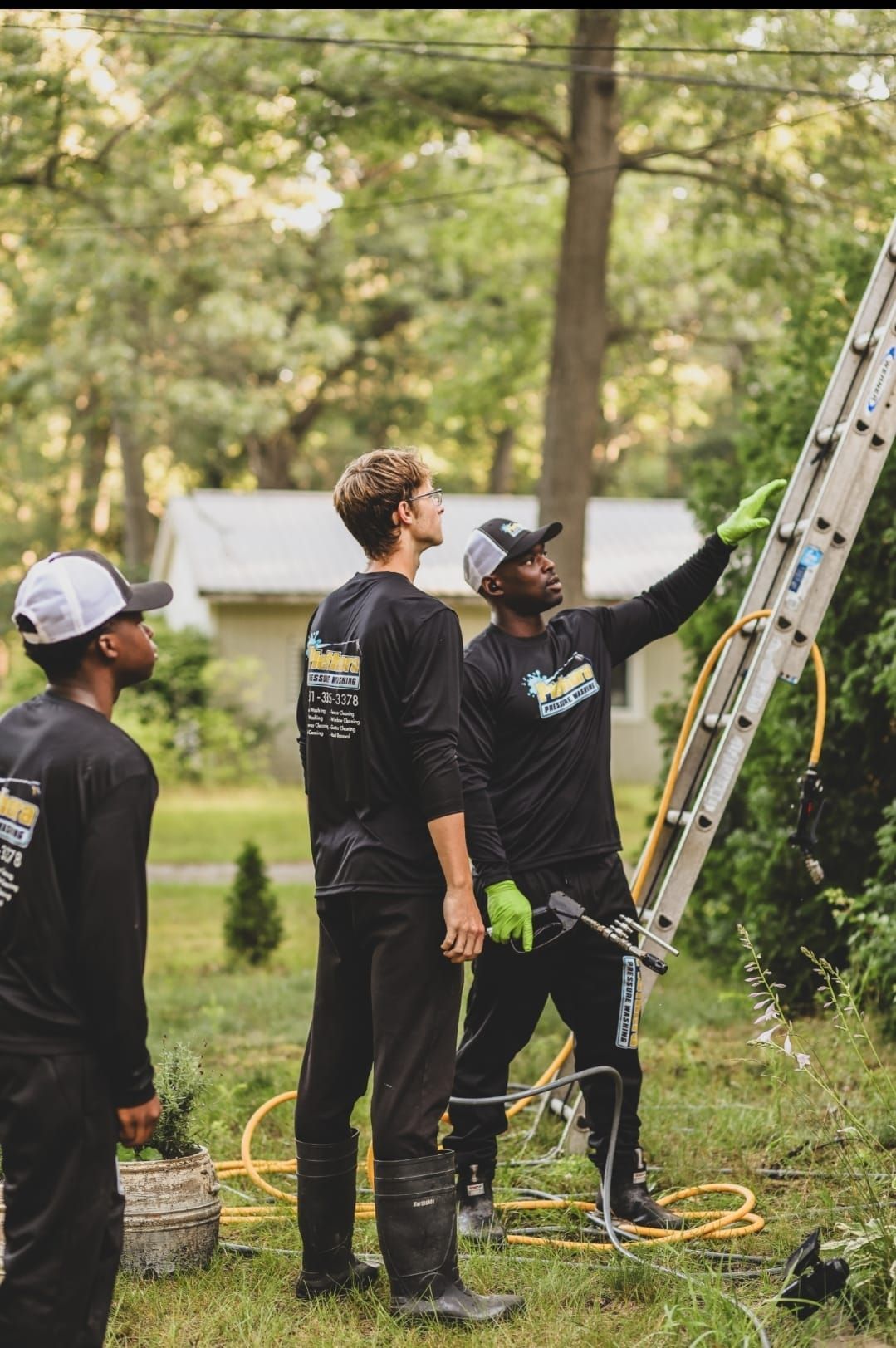 Three men are standing next to a ladder in a yard.