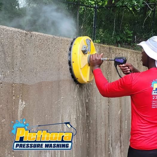 A man in a red shirt is using a pressure washer on a wall