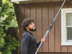 A man is holding a pole in front of a house.
