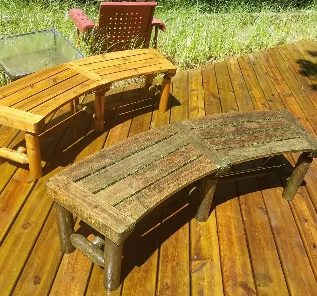 A wooden deck with a bench and chairs on it